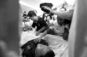 28日，兇手門多薩身著警服躺在棺木里。