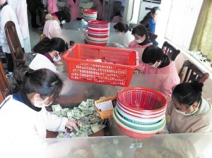 點鈔員們在低頭緊張地工作，她們每人每天都需要點鈔25箱1萬元以上。 陳暄 攝