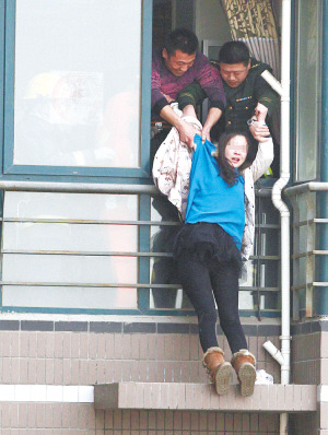 年輕女子在高樓窗外一小平臺坐了1個多小時后，被消防官兵拉進(jìn)屋內(nèi)。