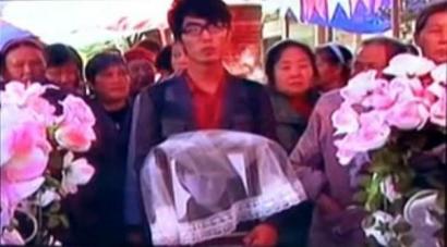 何濱捧著愛人遺像，送上深情一吻。（視頻截圖）