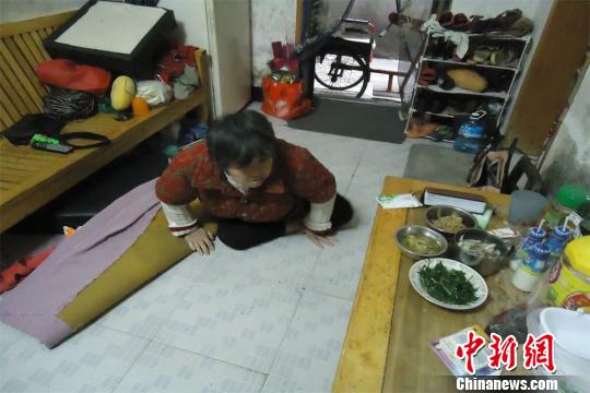 17日下午，56歲小兒麻痹癥患者張紅英爬在地板上找東西。 蘇路程 攝