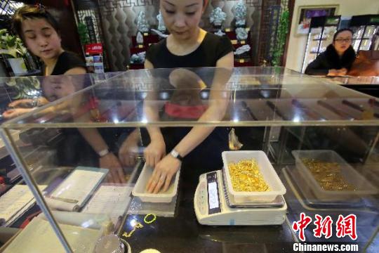 金店工作人員正在稱重。　張?jiān)啤z
