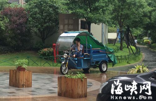 這名快遞哥騎行在小區(qū)通道內(nèi)，一邊接打手機，一邊還把腳架在車前欄桿上