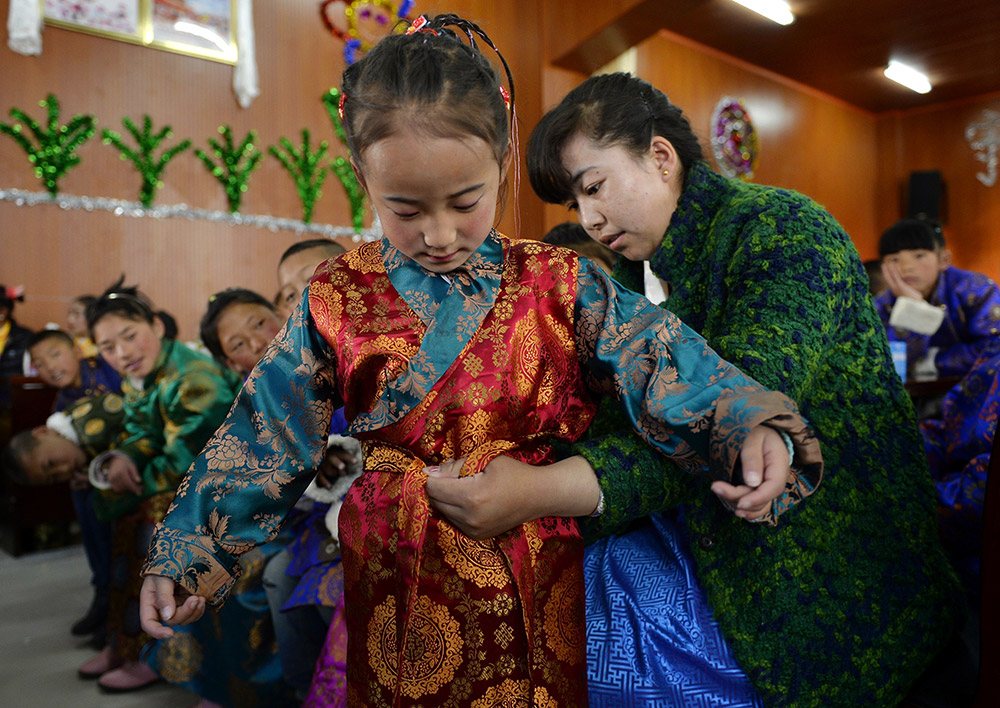 2月27日，在西藏自治區(qū)兒童福利院，來自拉薩市尼木縣的“愛心媽媽”德慶旺姆（右）在為來自那曲地區(qū)的嘎瑪曲宗換上節(jié)日盛裝。